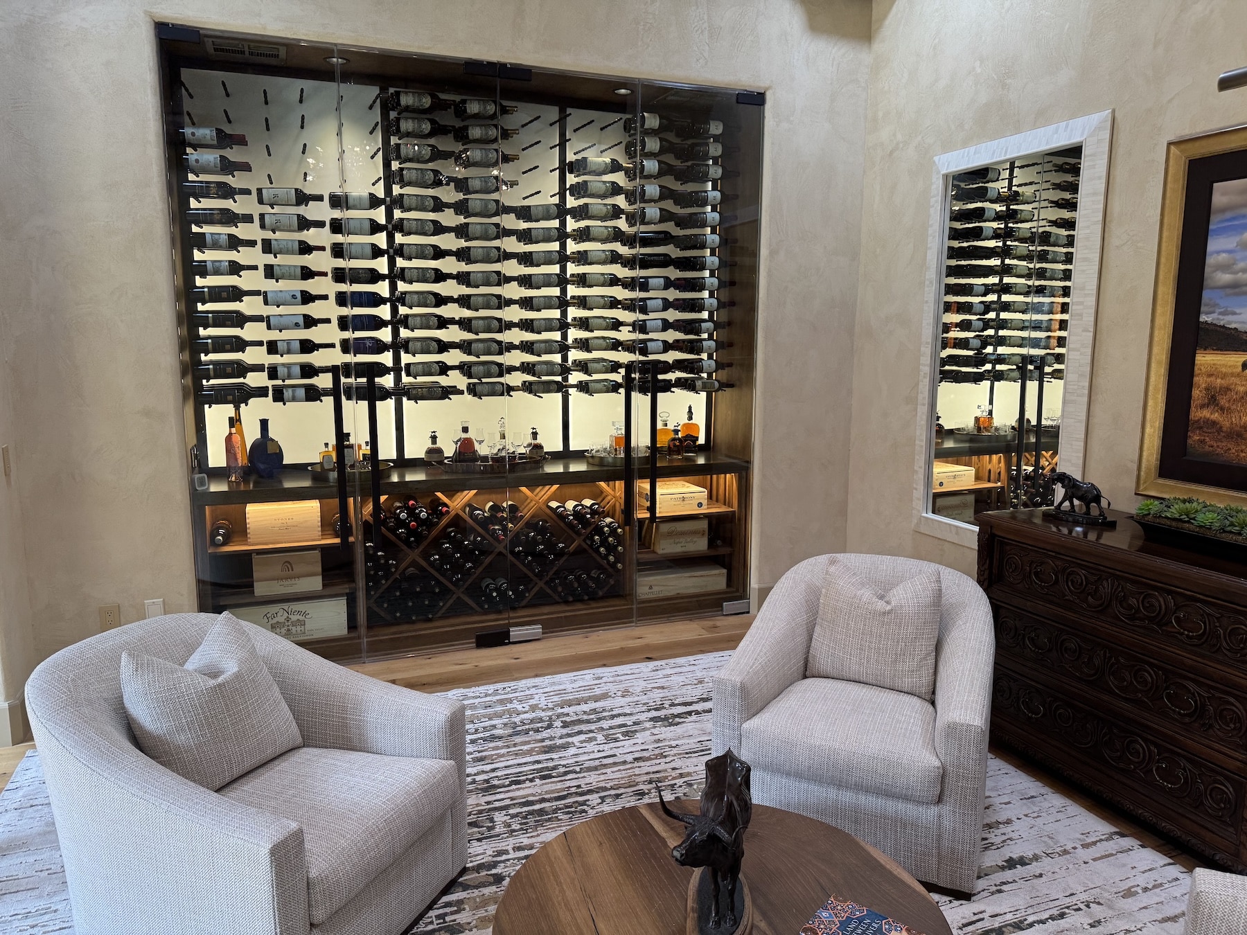 One of our best wine cellars for homes feature a striking 12-foot frameless glass entry, black metal peg racking, glowing acrylic panels, and warm wood elements - blending contemporary elegance with practical design.