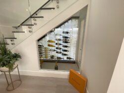 37 - A modern under stairs wine cellar with cable racking and a frameless glass door. Newport Beach wine cellar under stairs with glass door and cable racking