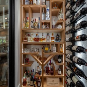 A tequila wall with custom-shaped storage compartments and an acrylic LED panel in the middle shelf.