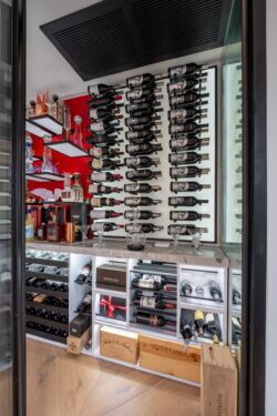(3) A bespoke wine cellar for home that combines custom shelving, a bold red accent wall, and curated liquor display.